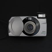 Fotocamera con sportellino aperto, visibile l’obiettivo zoom 28–70mm f/4.5–8.