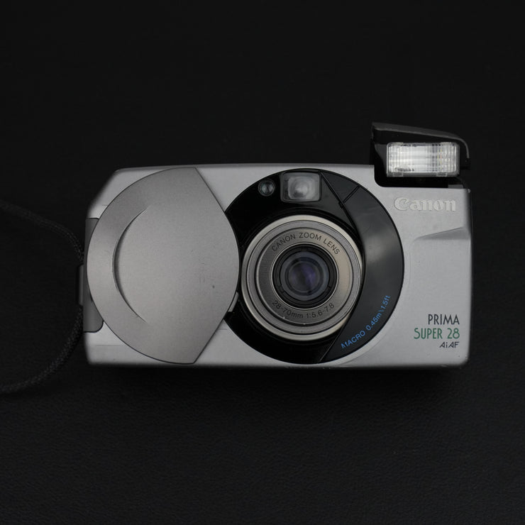 Fotocamera con sportellino aperto, visibile l’obiettivo zoom 28–70mm f/4.5–8.
