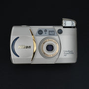 Fotocamera con sportellino aperto, visibile l’obiettivo zoom 38–70mm f/4.5–8.
