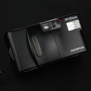 Vista frontale della fotocamera Olympus AF-10 Super con sportellino chiuso, design compatto e linee pulite.