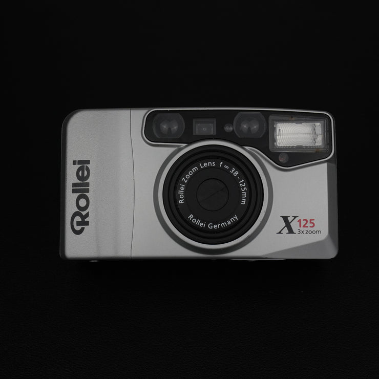 Vista frontale della fotocamera Rollei X125 con sportellino chiuso e design compatto.