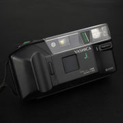 Fotocamera analogica Yashica J-Motor vista frontale con sportellino dell’obiettivo chiuso, design vintage