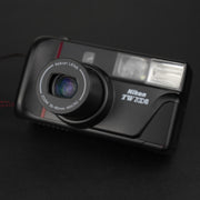 Fotocamera analogica Nikon TW Zoom frontale con sportellino aperto e obiettivo in estensione.