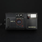 Olympus AF-1 vista frontale con sportellino aperto e obiettivo visibile